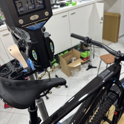 Bicicleta de montanha preta com balança digital mostrando peso em oficina
