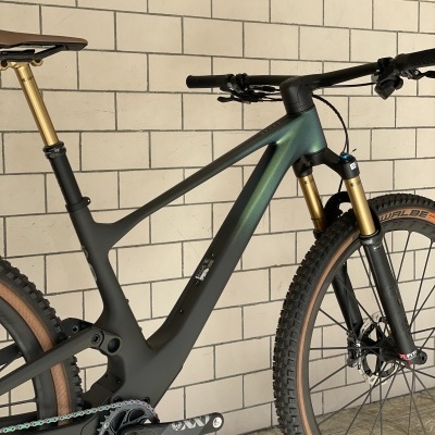 Bicicleta de montanha preta e verde com suspensão dourada e pneus Schwalbe