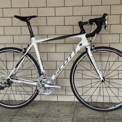 Bicicleta de estrada branca e preta com logótipo SCOTT encostada a parede de azulejos