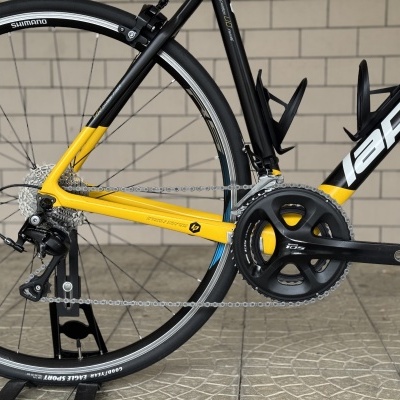 Bicicleta de estrada Lapierre preta e amarela com componentes Shimano 105 e pneus Goodyear Eagle Sport