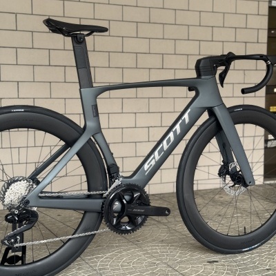 Bicicleta de estrada cinza fosco SCOTT com componentes Shimano 105 e rodas aerodinâmicas Schwalbe.