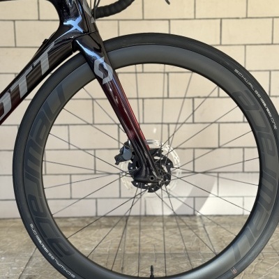 Roda dianteira de bicicleta com aro preto e pneu Schwalbe em fundo de parede de azulejos