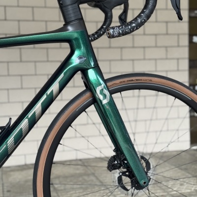 Bicicleta de estrada verde metálico com guiador preto e pneu Schwalbe One castanho