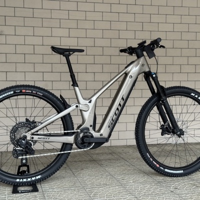 Bicicleta de montanha elétrica cinzenta SCOTT com pneus Maxxis e suspensão preta
