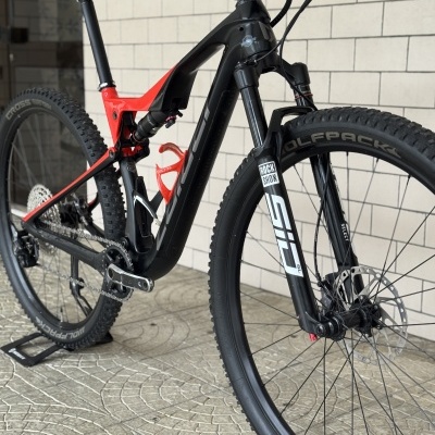 Bicicleta de montanha preta e vermelha com suspensão dianteira ROCK SHOX e pneus WOLFPACK.