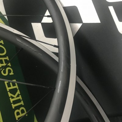 Roda de bicicleta preta com faixa branca, raios pretos e texto 'BIKE SHOP' em fundo verde.