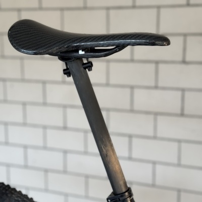 Selim de bicicleta preto com padrão de fibra de carbono e canote preto