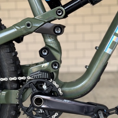 Quadro verde metálico de bicicleta de montanha com suspensão e componentes visíveis