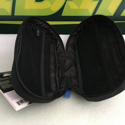 Estojo rígido preto aberto com bolsos interiores e cartão informativo