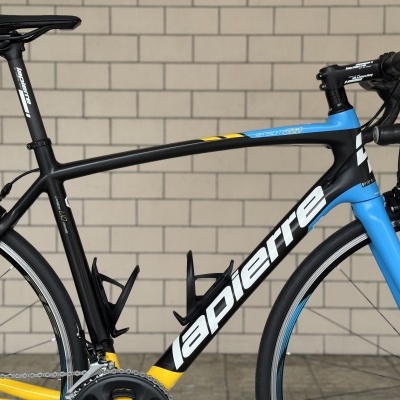 Bicicleta de estrada preta com detalhes azuis e amarelos e texto lapierre