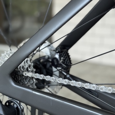 Bicicleta cinza escuro com corrente prateada e cassete metálico na roda traseira