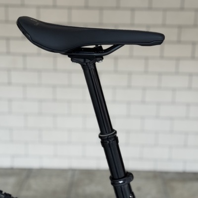 Sela de bicicleta preta montada num suporte preto com parede branca de azulejos ao fundo