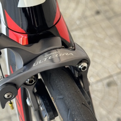 Freio de bicicleta Shimano Ultegra preto com pneu de estrada e quadro preto com detalhes vermelhos.