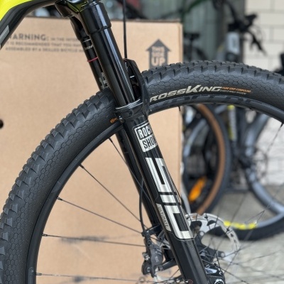 Pneu preto Continental Cross King com suspensão RockShox preta e parte do quadro amarelo fluorescente