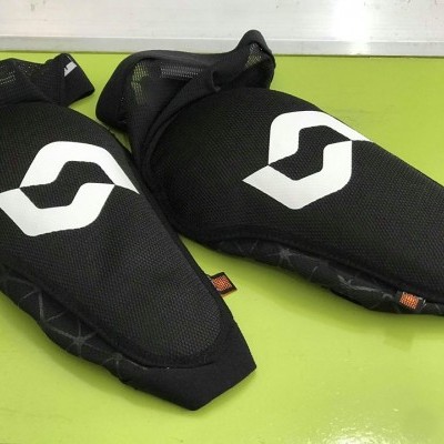 Duas joelheiras pretas com logotipo branco sobre fundo verde