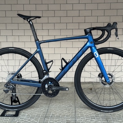 Bicicleta de estrada azul metálica SCOTT com pneus pretos e travão a disco