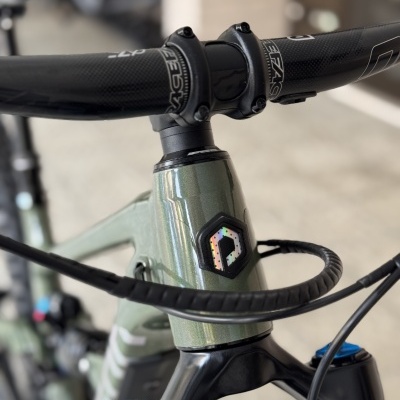 Detalhe do quadro e guiador de bicicleta verde metálica com componentes pretos e azuis