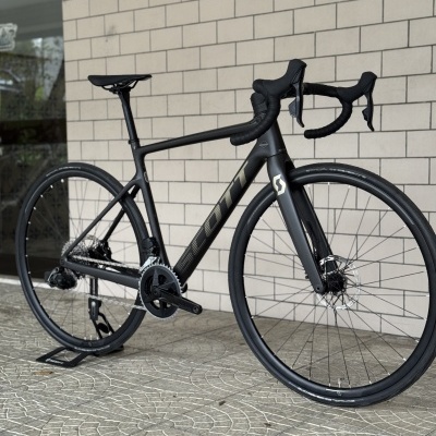 Bicicleta de estrada preta com estrutura em carbono e texto SCOTT