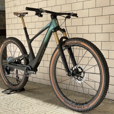 Bicicleta de montanha cinza esverdeada com pneus castanhos e suspensão dianteira