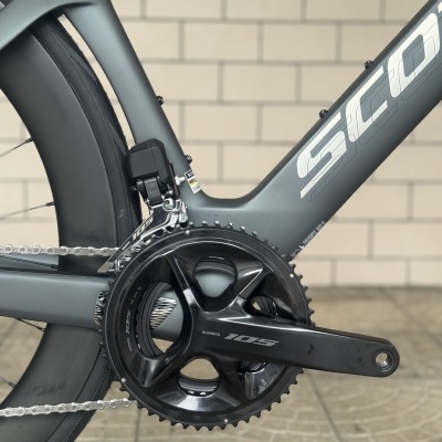 Close-up da pedaleira e quadro de bicicleta de estrada cinza fosco com componentes Shimano 105.