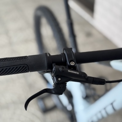 Guiador de bicicleta preto com manete de travão Shimano e quadro branco desfocado