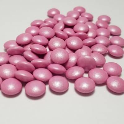 Comprimidos redondos rosa metálico sobre superfície branca