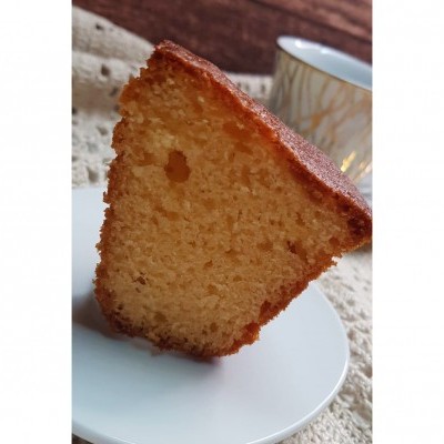 Fatias de bolo amarelo esponjoso num prato branco com copo de vidro ao fundo