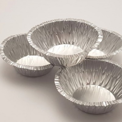 Formas redondas de alumínio ondulado prateado sobre superfície branca