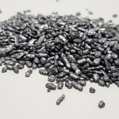 Pequenos grânulos metálicos pretos sobre superfície branca