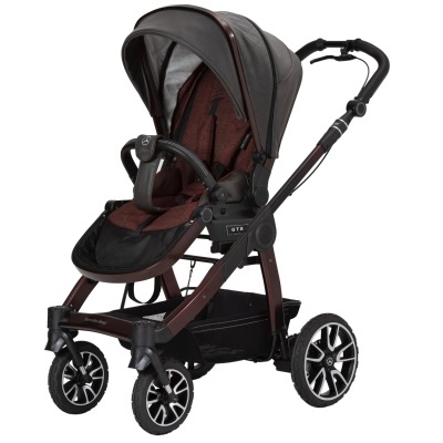Carrinho de bebé com estrutura castanho, assento vermelho e capota preta.
