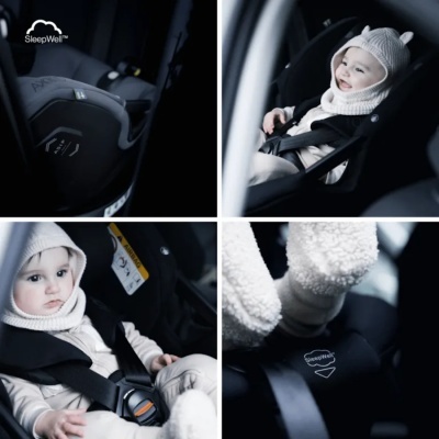 Cadeira de carro preta com bebé vestido de branco e cinto de segurança