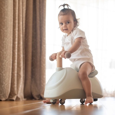 Criança num carrinho de passeio bege com rodas e guiador de madeira