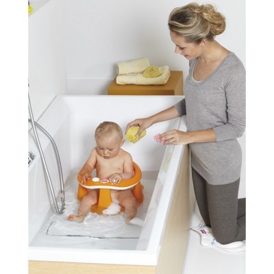 Criança sentada em cadeira de banho laranja numa banheira branca com mulher junto a si e toalhas no rebordo