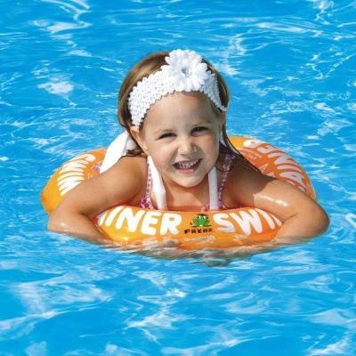 Criança numa piscina com boia laranja com texto 'SUMMER SWIM'