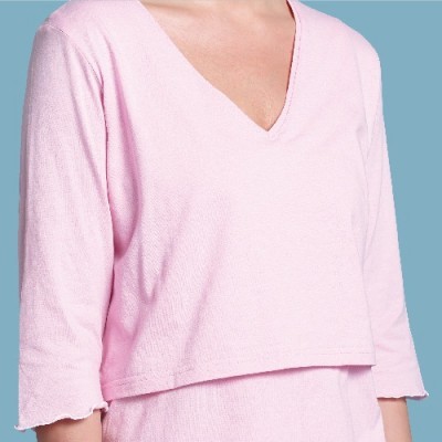 Top rosa de manga 3/4 com decote em V sobre fundo azul.