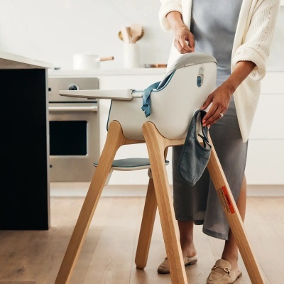 Cadeira alta para bebé branca com pés de madeira numa cozinha moderna