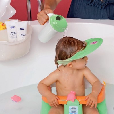 Criança na banheira a tomar banho com boné de proteção verde