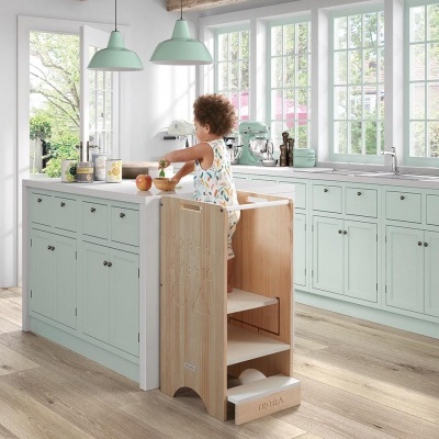 Criança em apoio de aprendizagem de madeira natural em cozinha com armários verdes claros e bancada branca