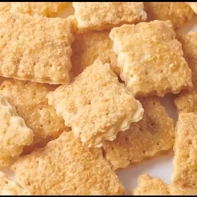 Biscoitos quadrados crocantes cor dourada sobre superfície branca