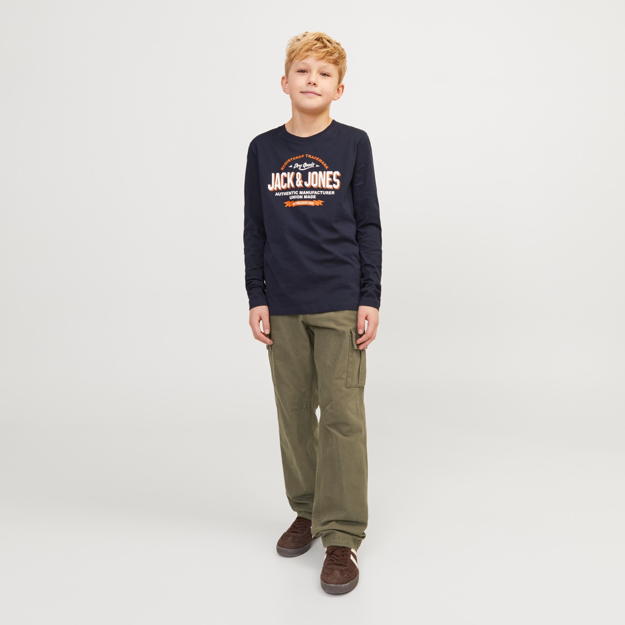 Rapaz com camisola azul escura JACK & JONES e calças verdes em fundo branco