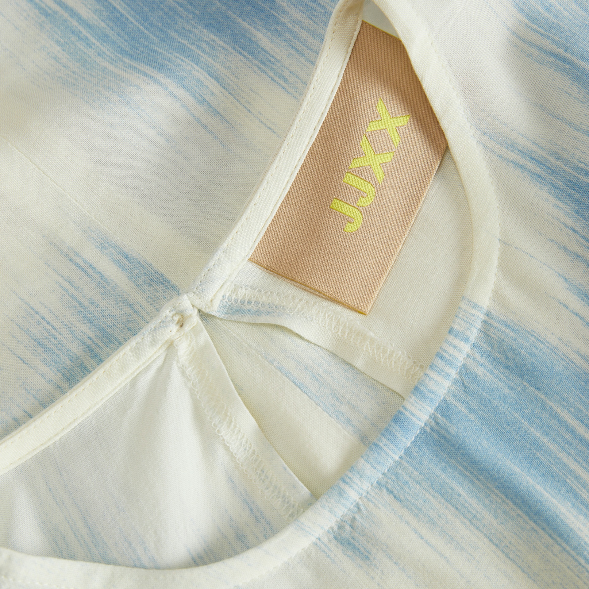 Camisola com padrão azul e branco e etiqueta com texto amarelo