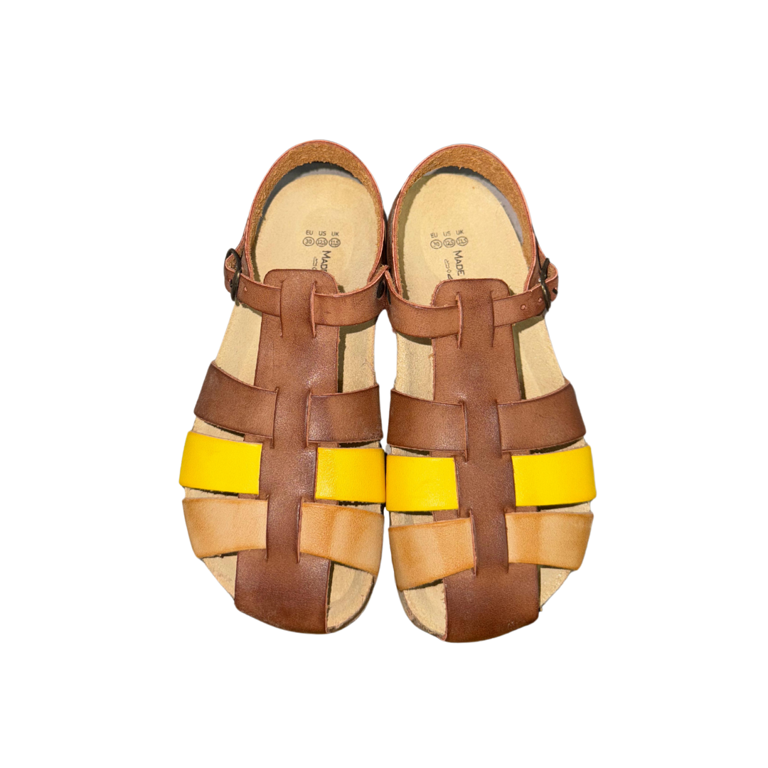 Sandálias infantis em pele castanha, bege e amarelo sobre fundo branco