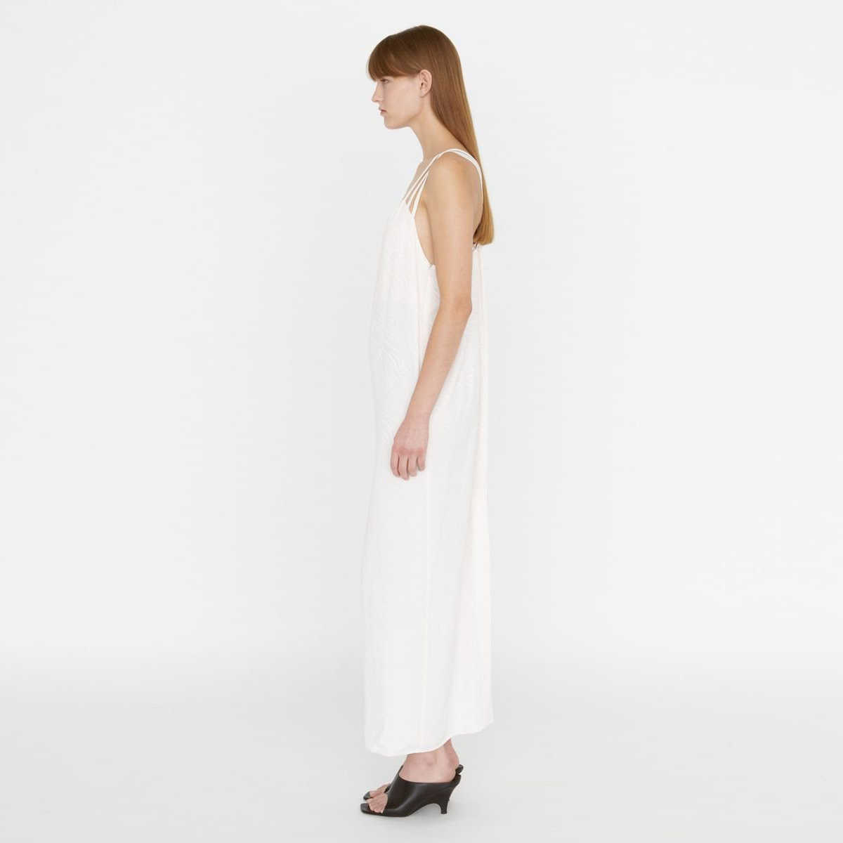 Vestido branco comprido de alças finas e sandálias pretas em modelo de perfil