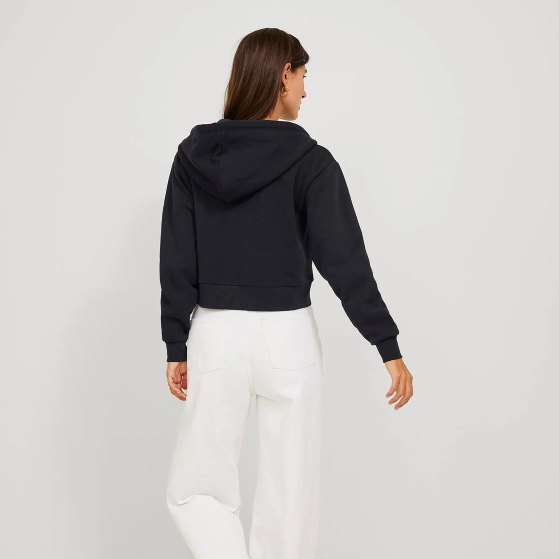 Casaco com capuz preto curto visto por trás com calças brancas