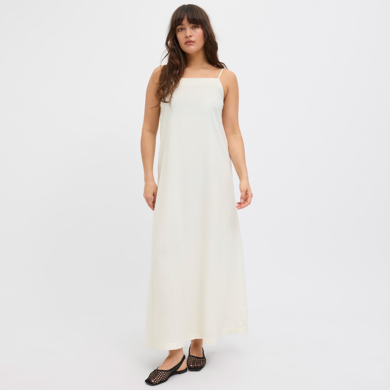 Mulher a usar vestido branco comprido de alças finas e sapatos pretos