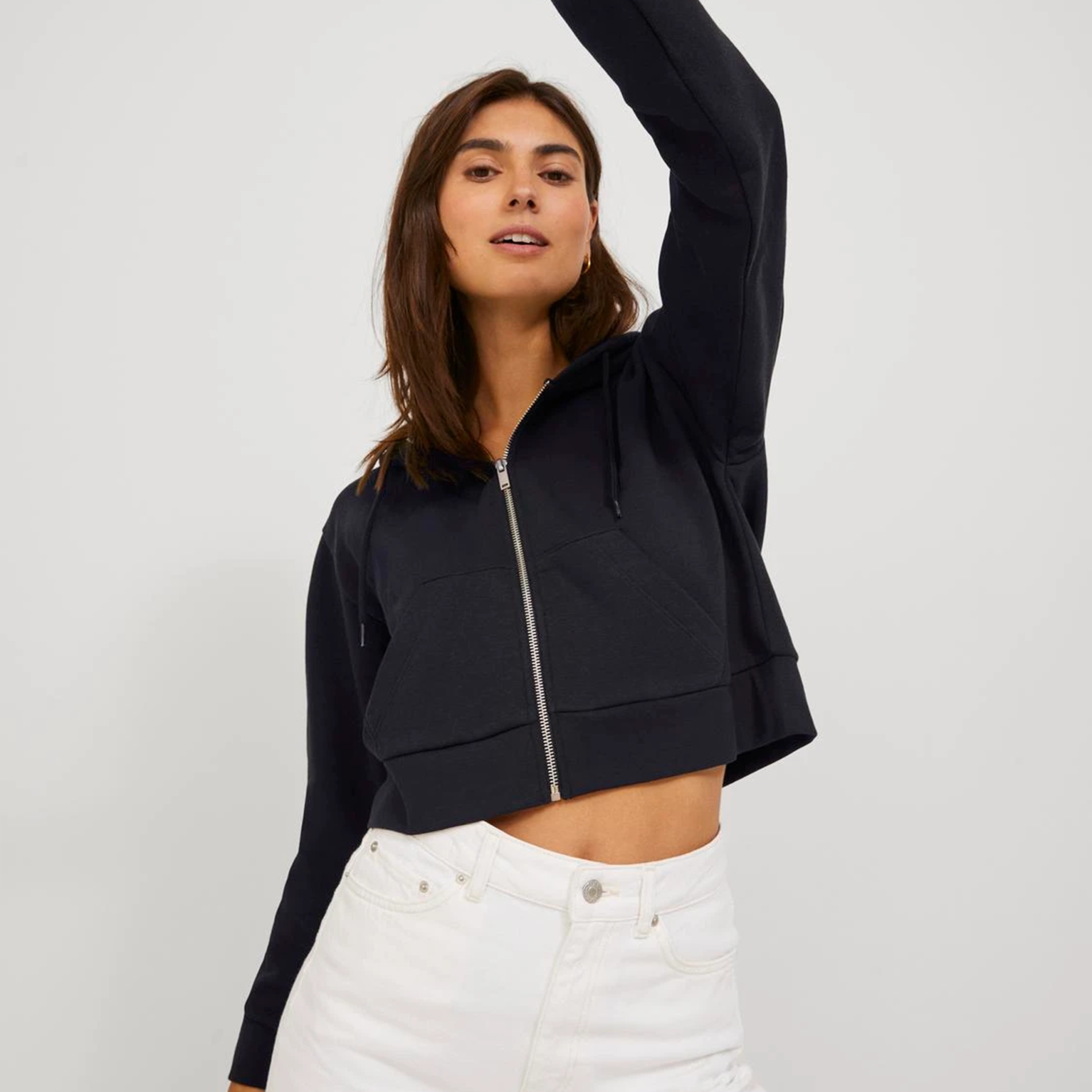 Casaco preto com capuz e fecho de correr, combinado com calças brancas