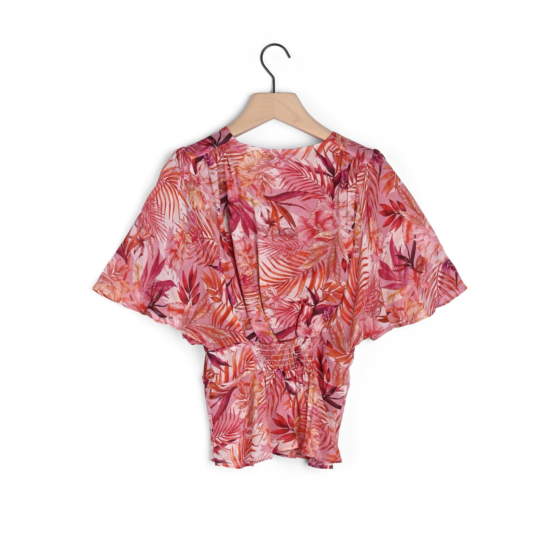 Blusa feminina rosa com padrão floral pendurada em cabide de madeira