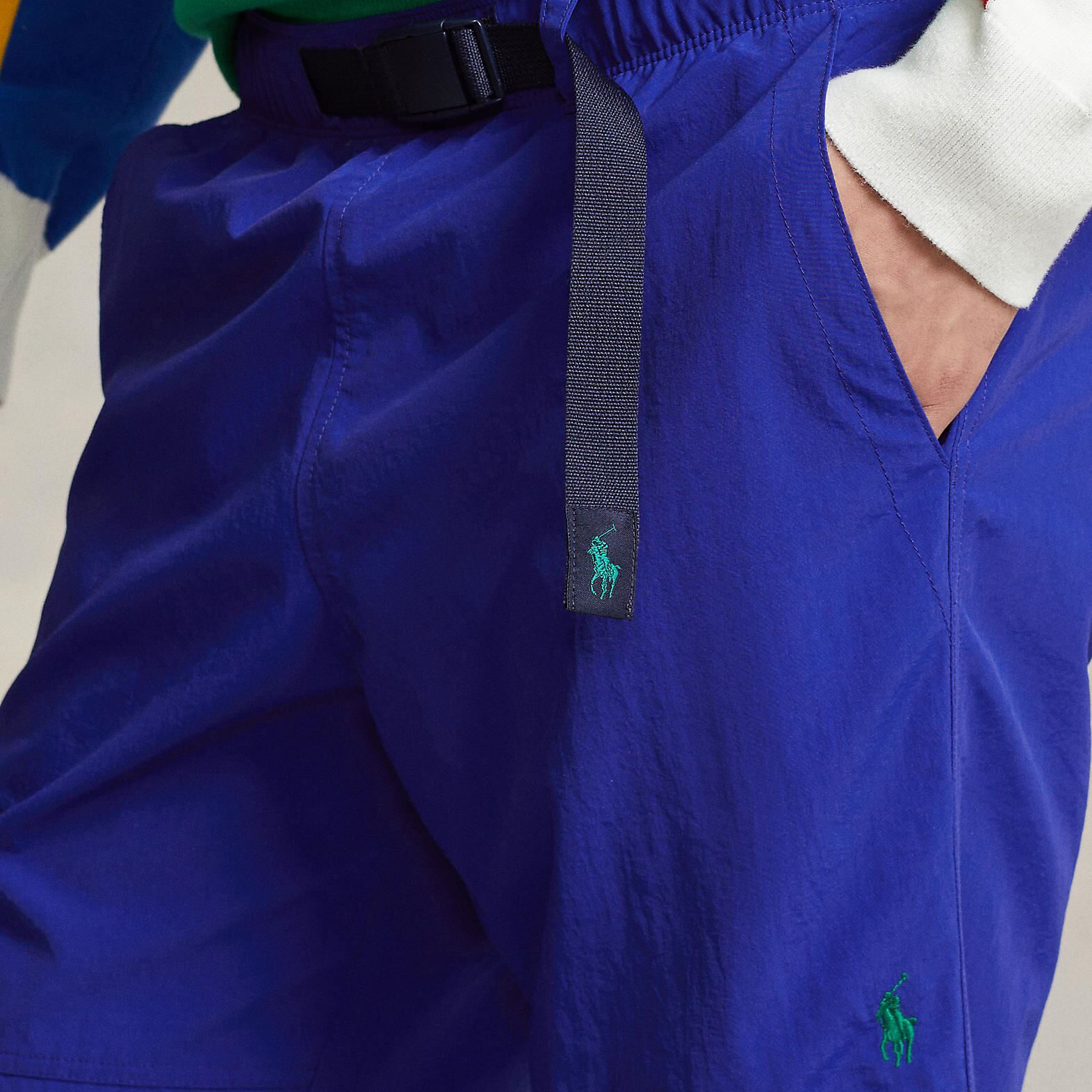 Calças desportivas azuis com cinto preto de tecido e logótipo verde bordado