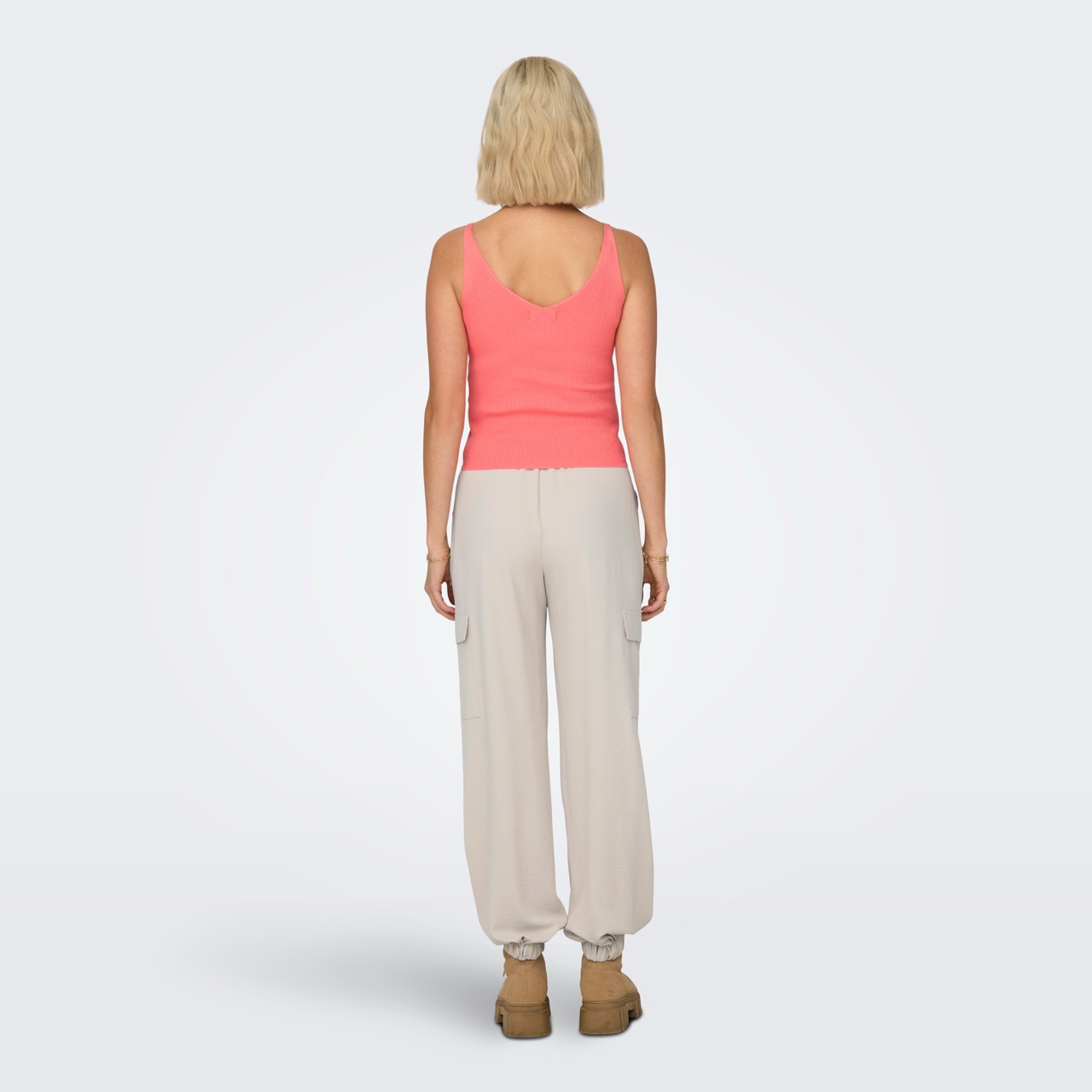 Mulher vestindo top rosa coral e calças bege vista de costas