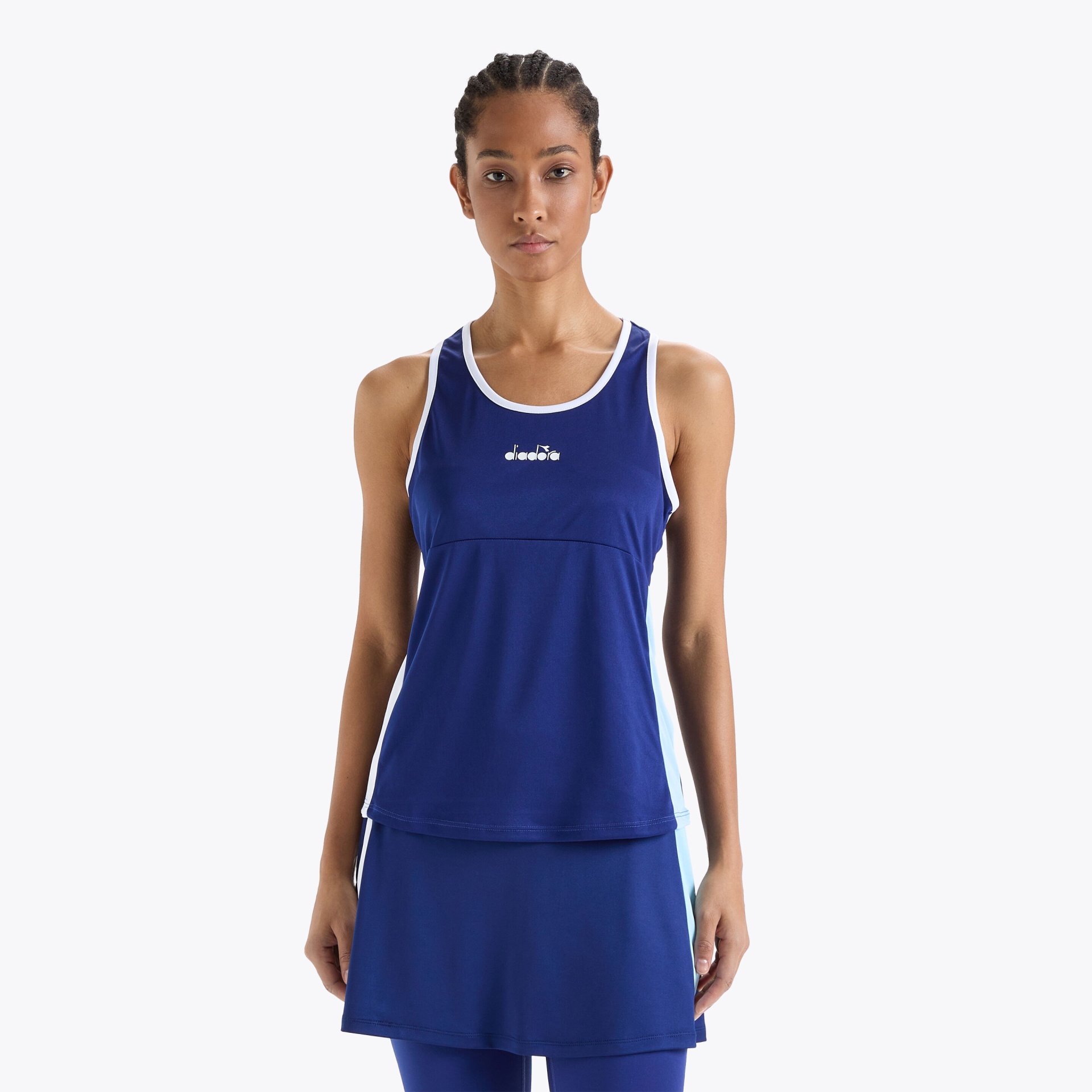 Top desportivo feminino azul escuro com detalhes brancos e logótipo DIADORA, com saia curta azul escura.